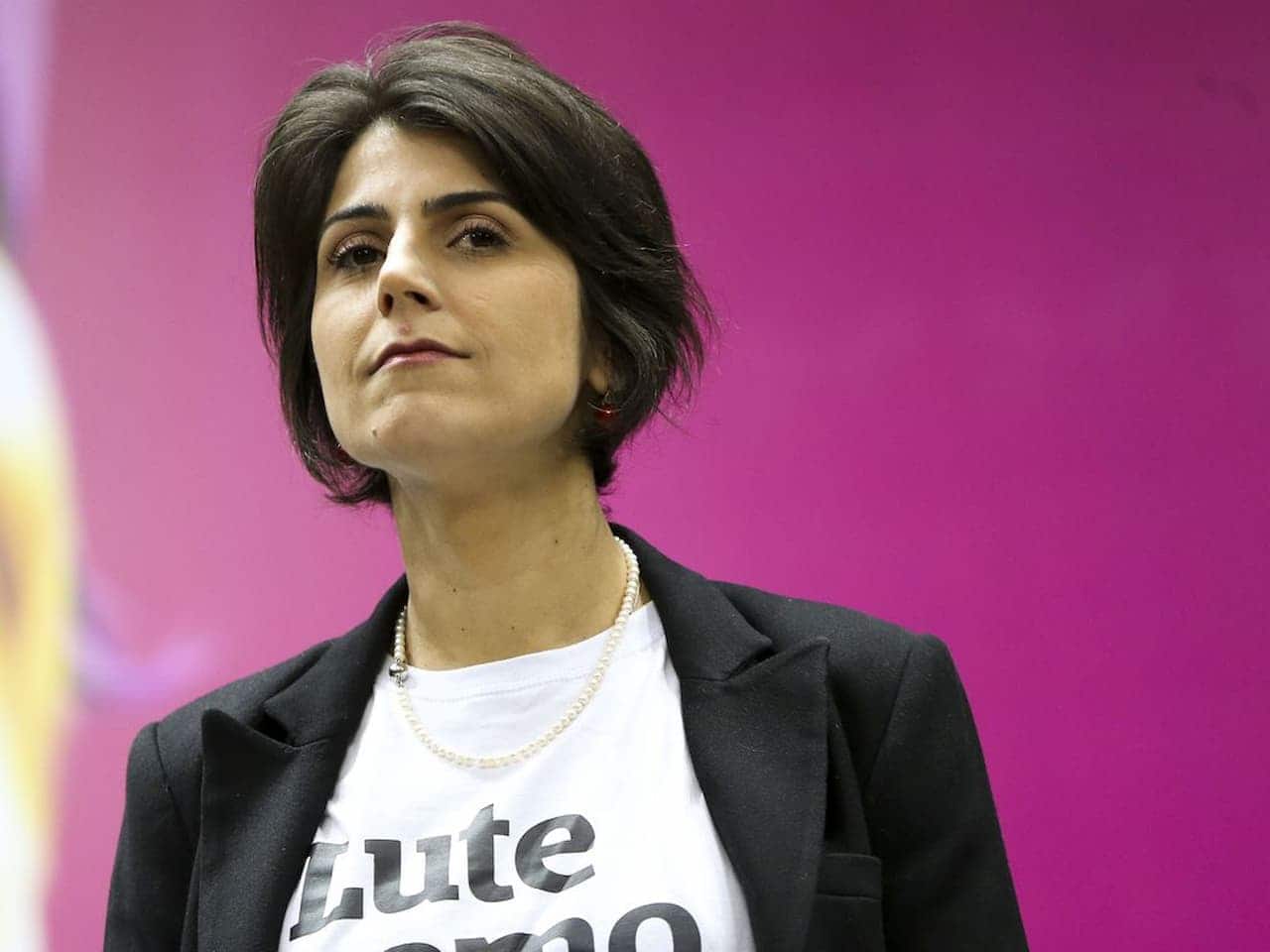 Foto de Manuela D'Ávila com expressão séria e fundo rosa