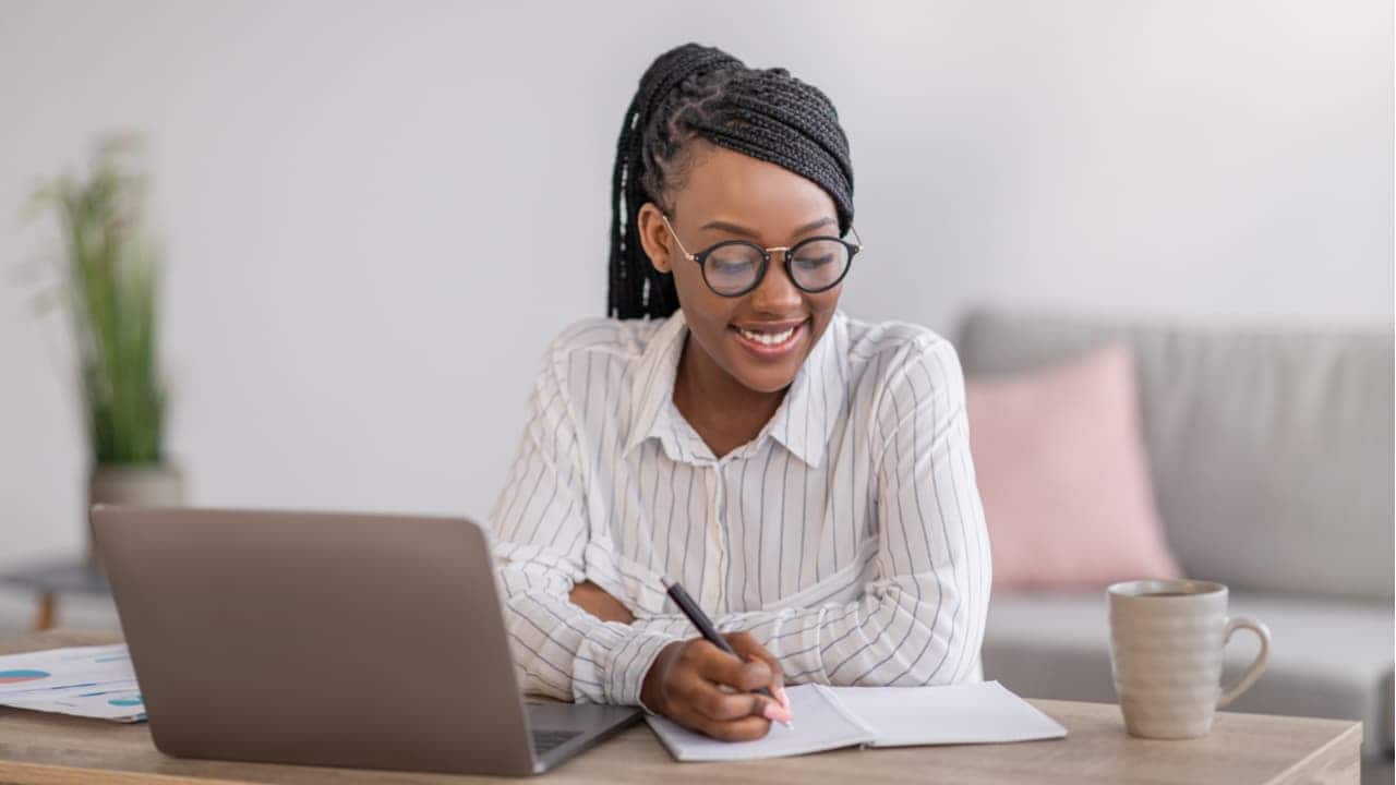 mulher estudando com cursos gratuitos pelo computador enquanto sorri