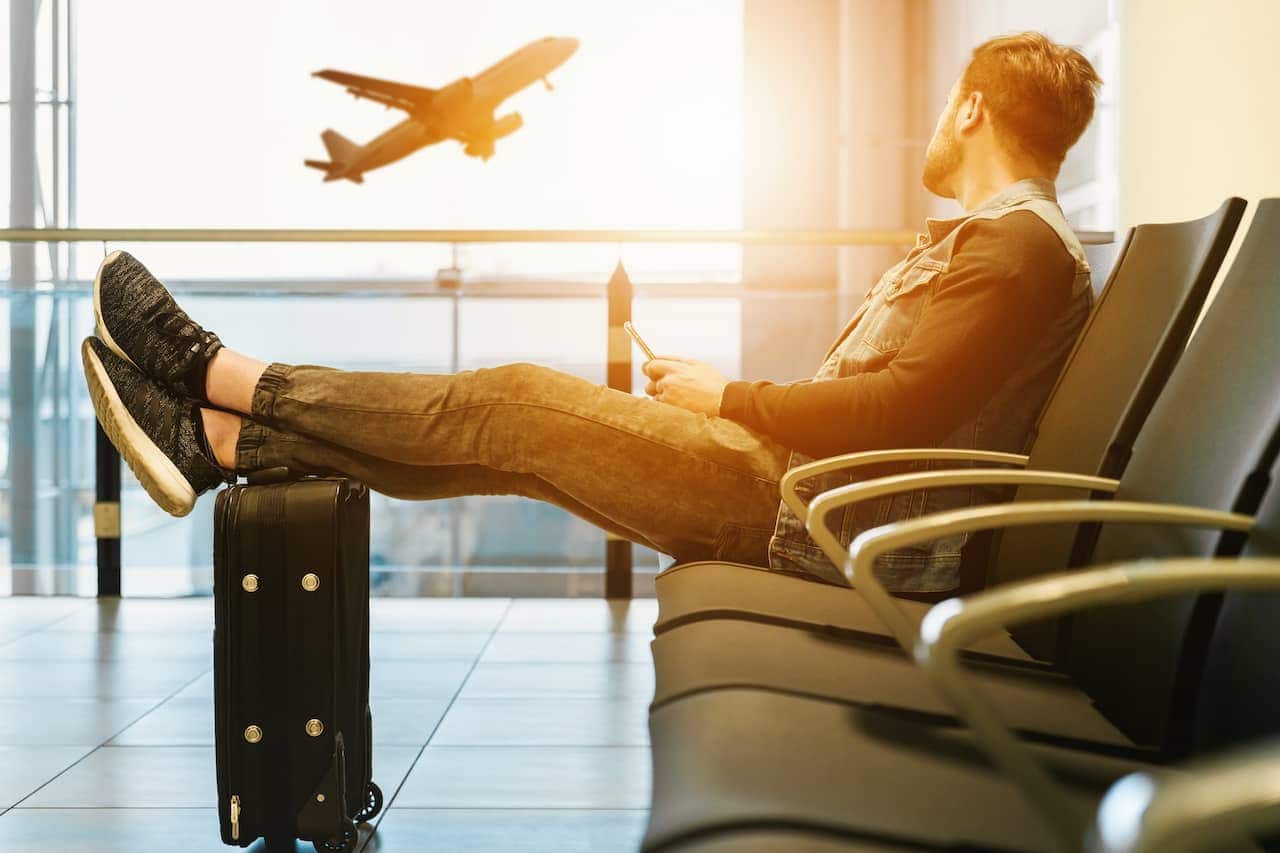 Homem turista sentado em aeroporto olhando avião decolando