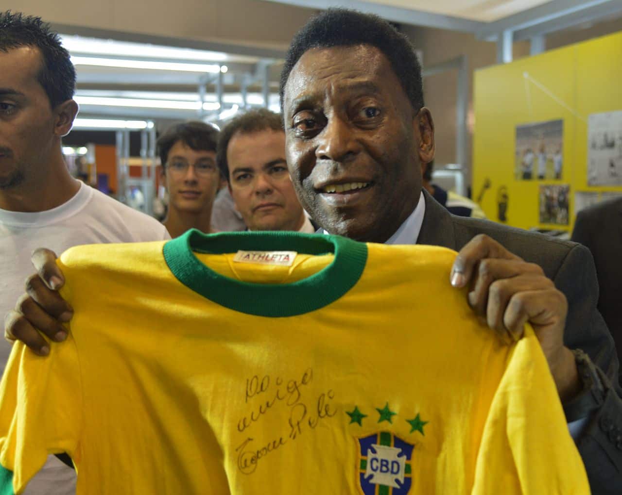 Imagem de Pelé segurando um uniforme da seleção brasileira de futebol.