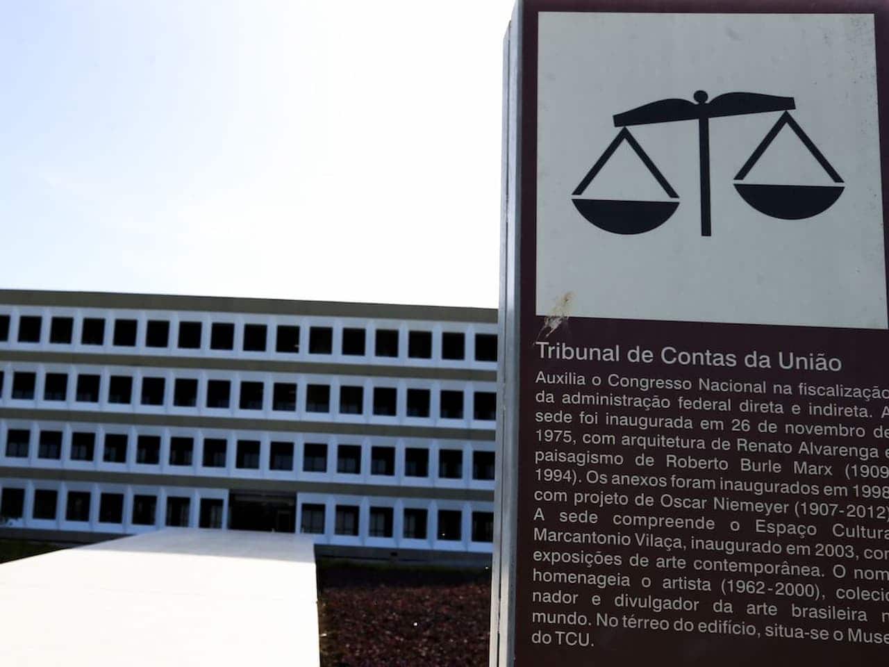 Placa do Tribunal de Contas da União com prédio sede ao fundo