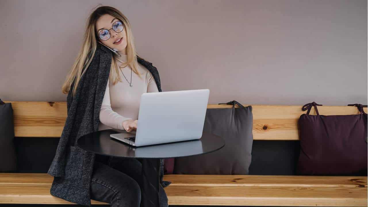 Imagem de uma mulher trabalhando no celular e notebook