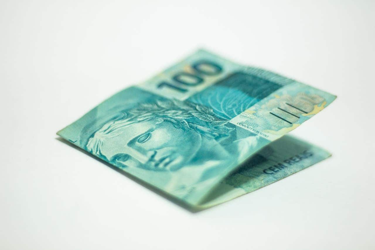 Imagem com uma nota de 100 reais dobrada ao meio.