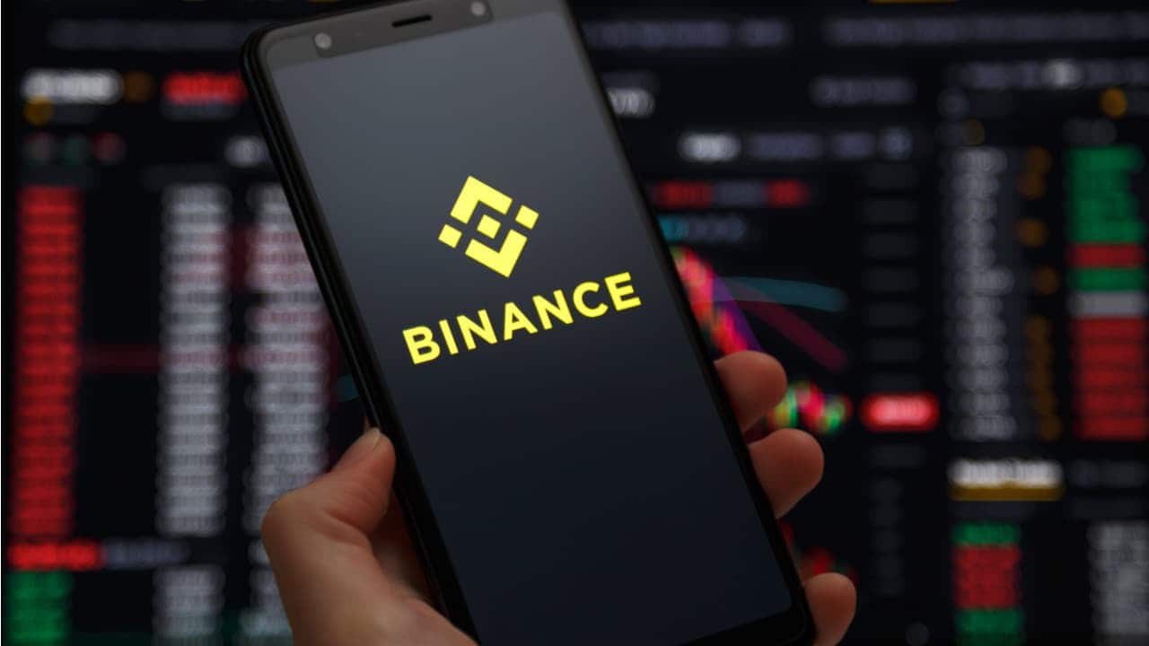 Mão segurando celular com aplicativo da Binance