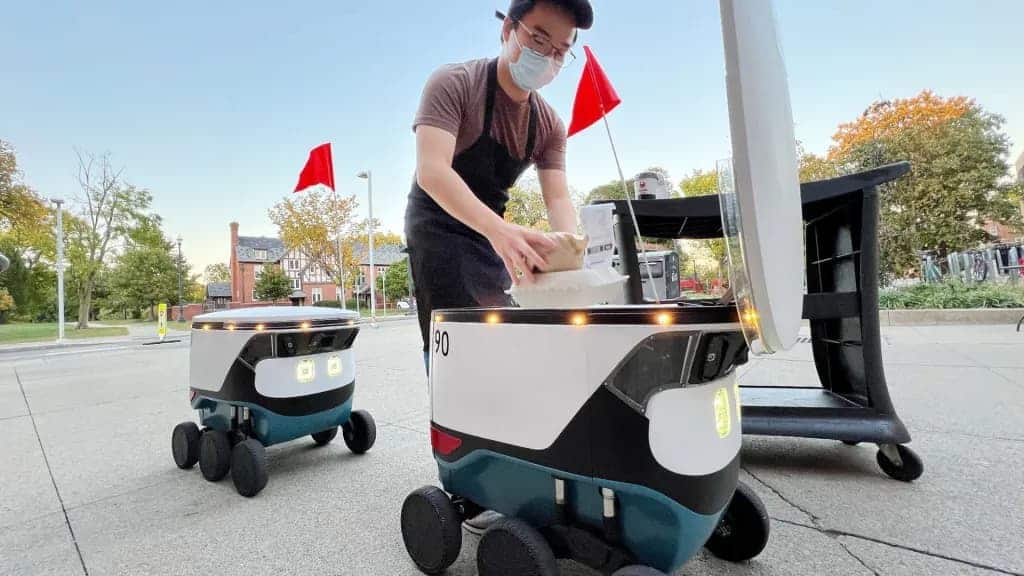 Homem com dois robôs de entrega do Uber Eats