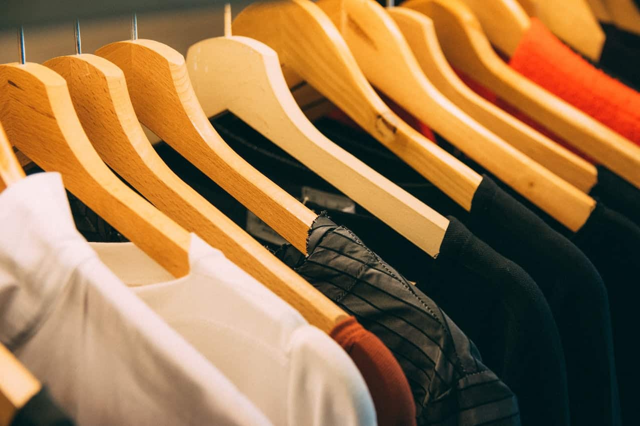 Uma arara com várias camisas postas nos cabides.