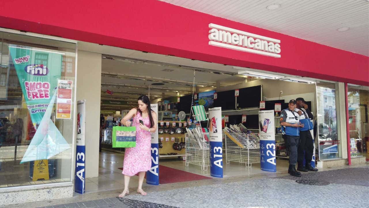 Fachada de umas das Lojas Americanas com uma cliente à porta
