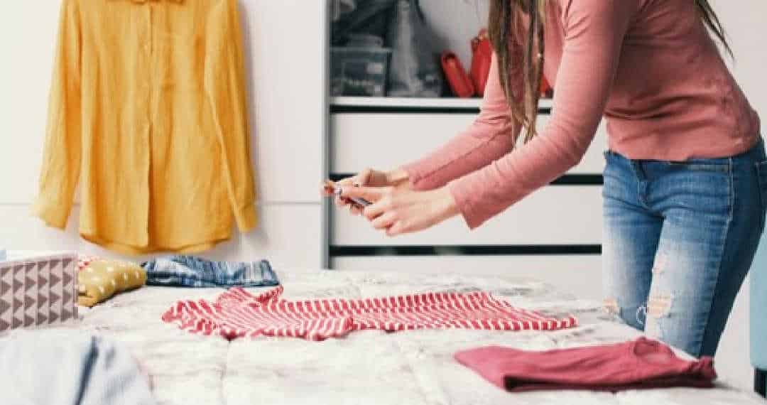 mulher tirando foto de roupas em cima da cama