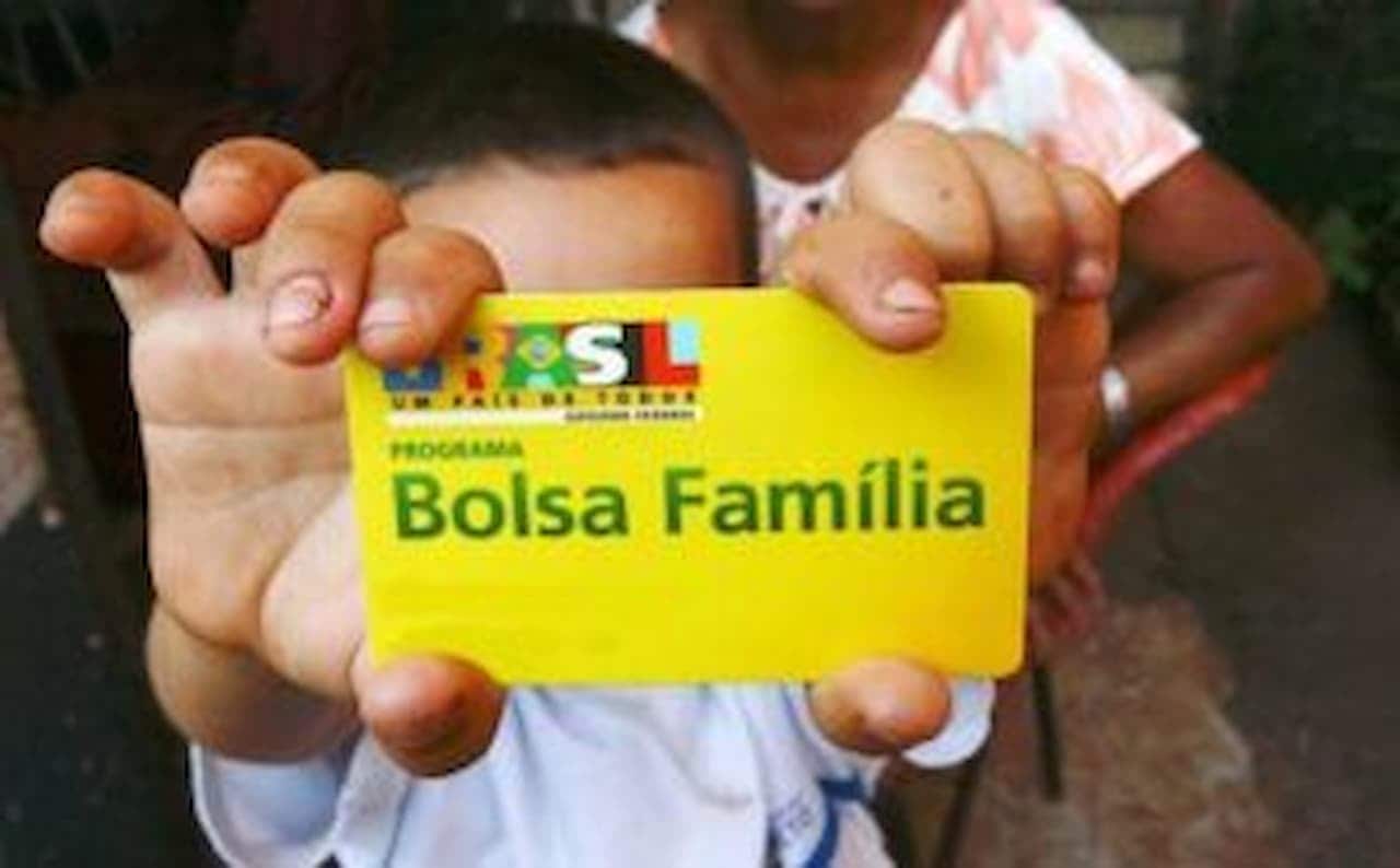 Criança segurando cartão do Bolsa Família