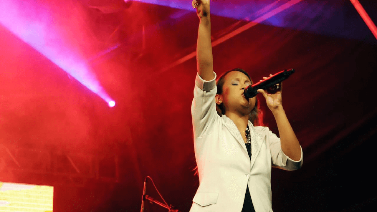 Imagem cantora gospel Bruna Karla com mão pra cima cantando