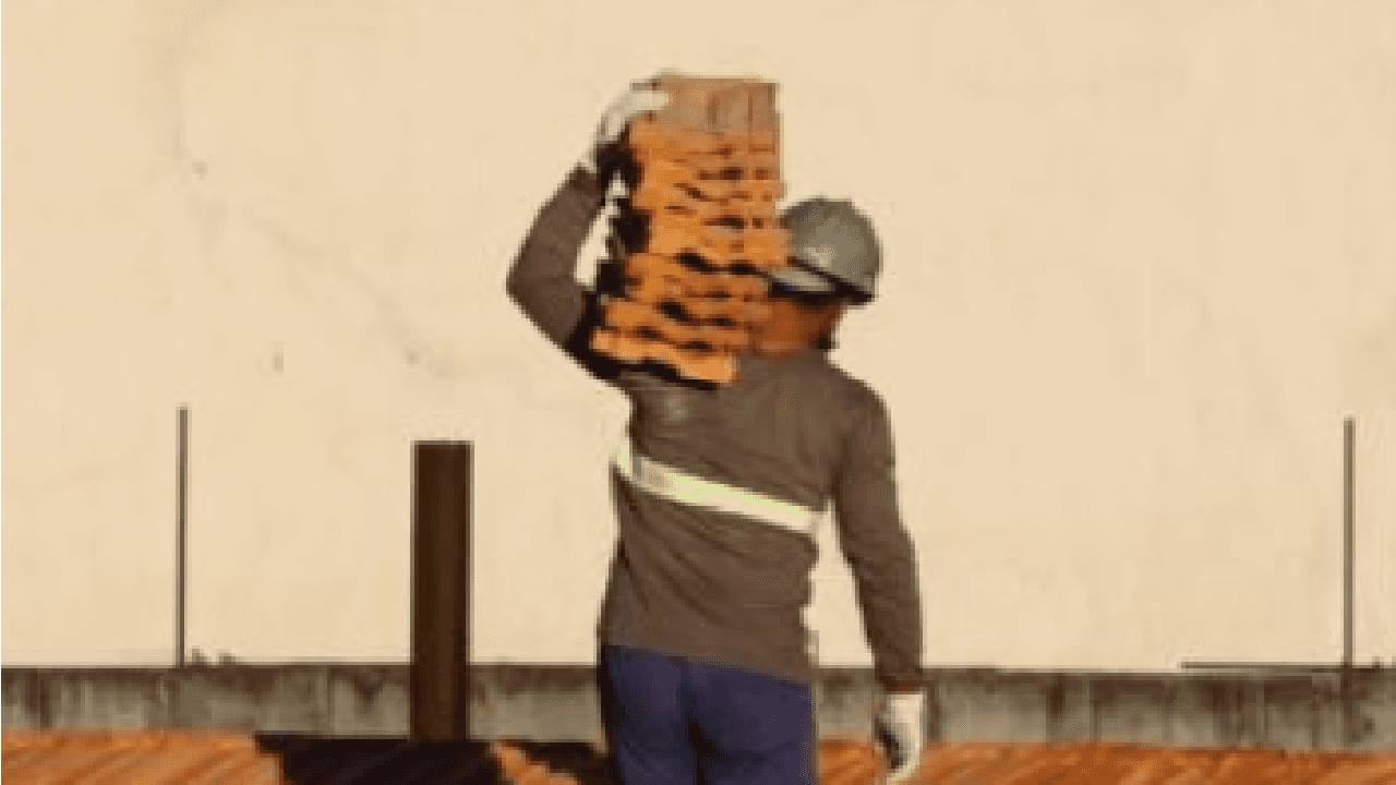 Pedreiro carregando materiais de construção no ombro obra