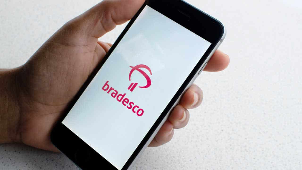celular na mão com aplicativo do banco Bradesco na tela