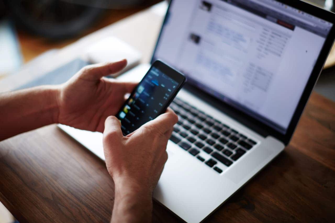 Usuário usa o smartphone enquanto utiliza também o notebook