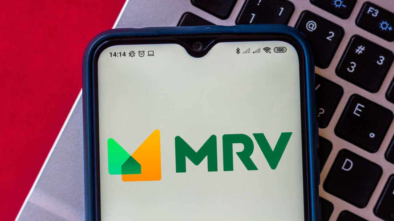 celular com logo da MRV na tela inicial. O aparelo está em cima de um teclado de notebook.