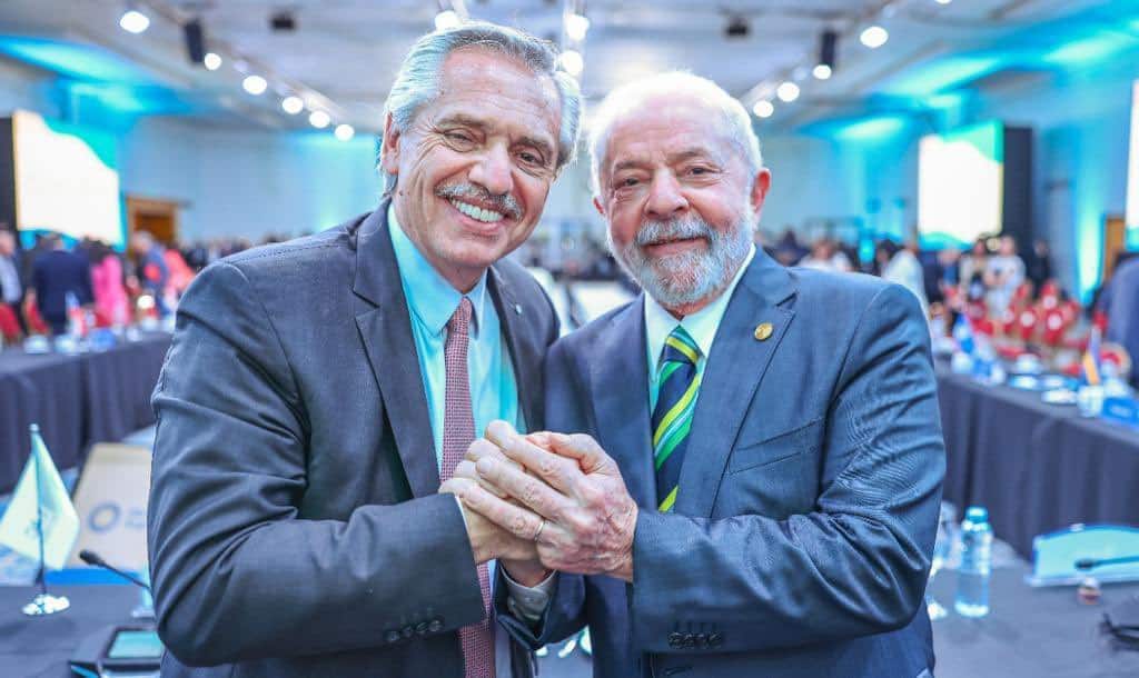 Presidente da Argentina, Alberto Fernández, e presidente do Brasil, Lula, sorrindo e posando para foto com as mãos entrelaçadas.
