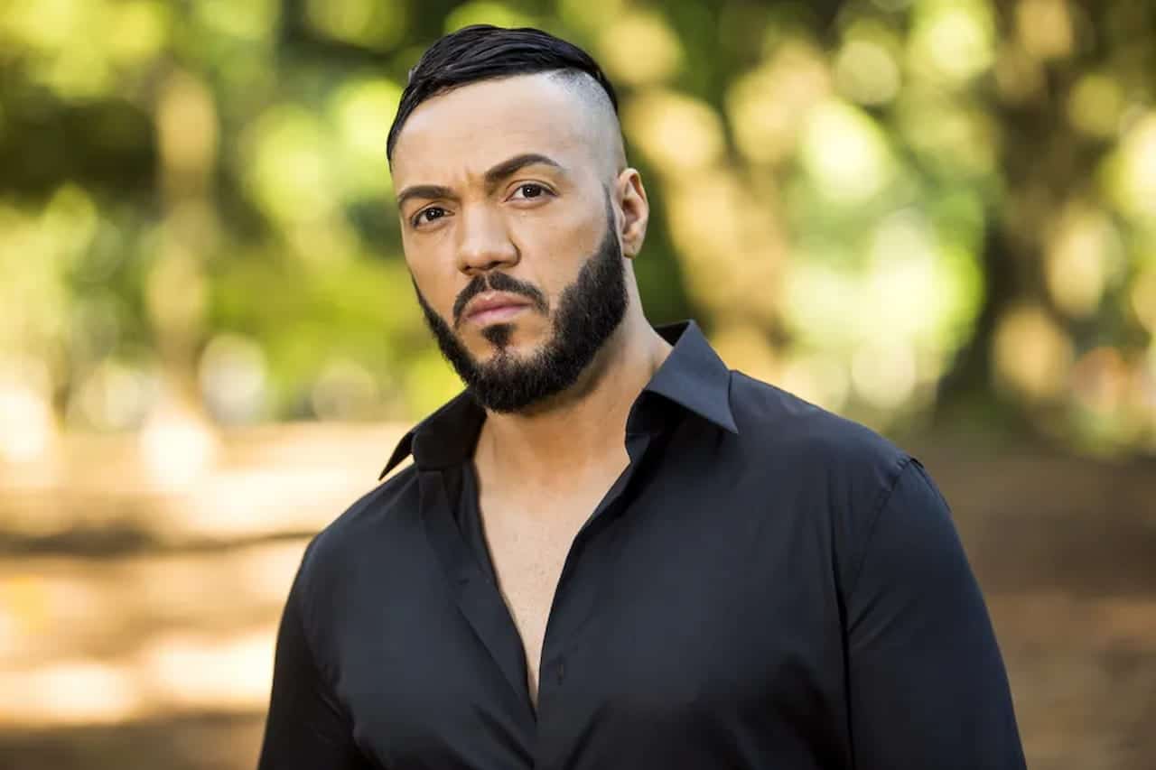 Cantor Belo posa para foto vestido com uma camisa social na cor preta