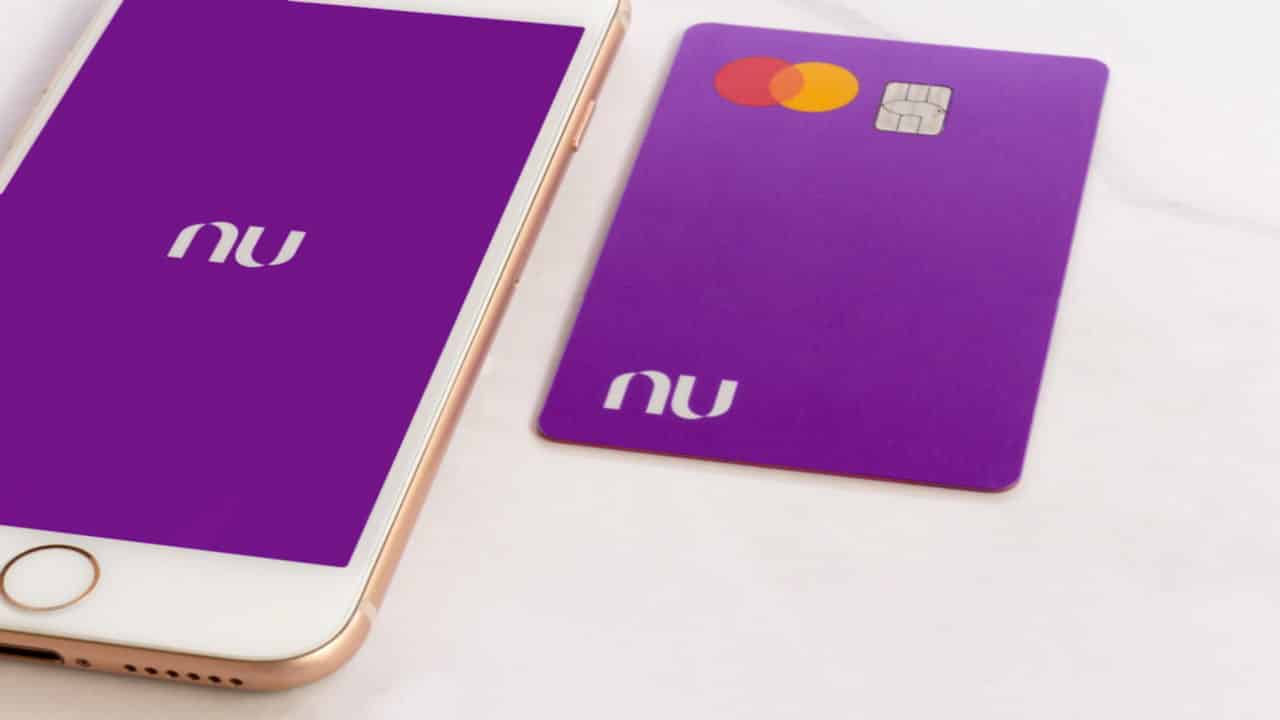 Cartão Nubank ao lado de celular que exibe a logo do banco digital