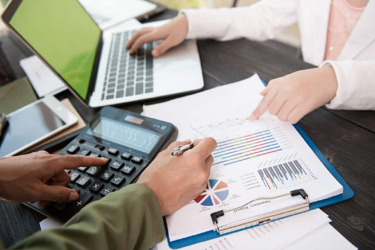Imagem de duas pessoas calculando e analisando documentos. isenção
