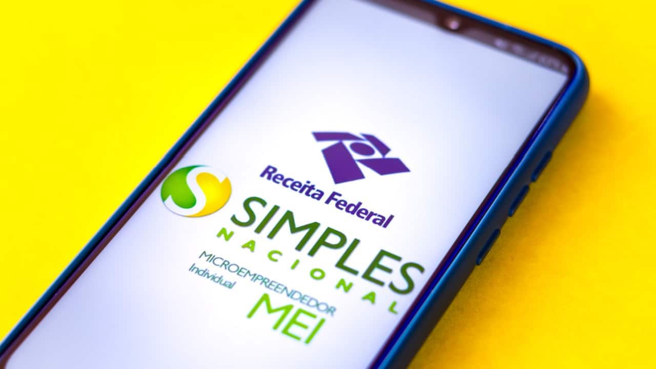 Celular sobre fundo amarelo mostrando logos do Simples Nacional, do MEI e da Receita Federal