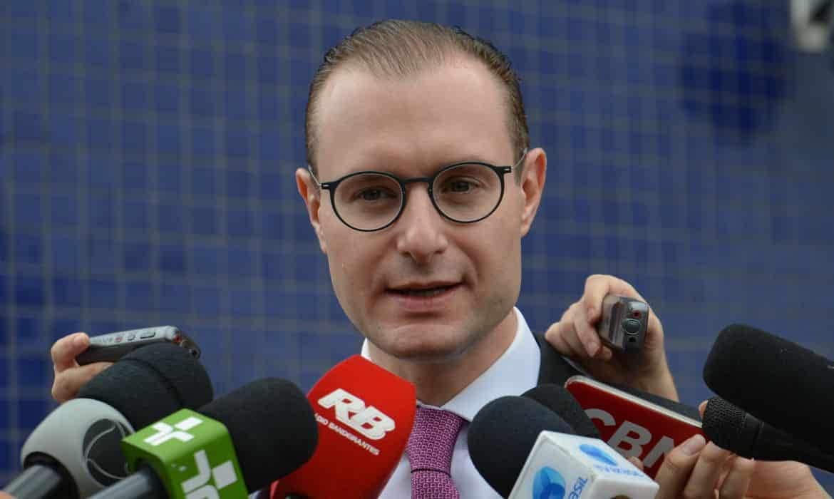 Cristiano Zanin, advogado do presidente Lula, rodeado por microfones de várias emissoras durante entrevista