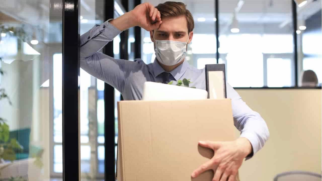 Um homem segurando uma caixa saindo de uma empresa