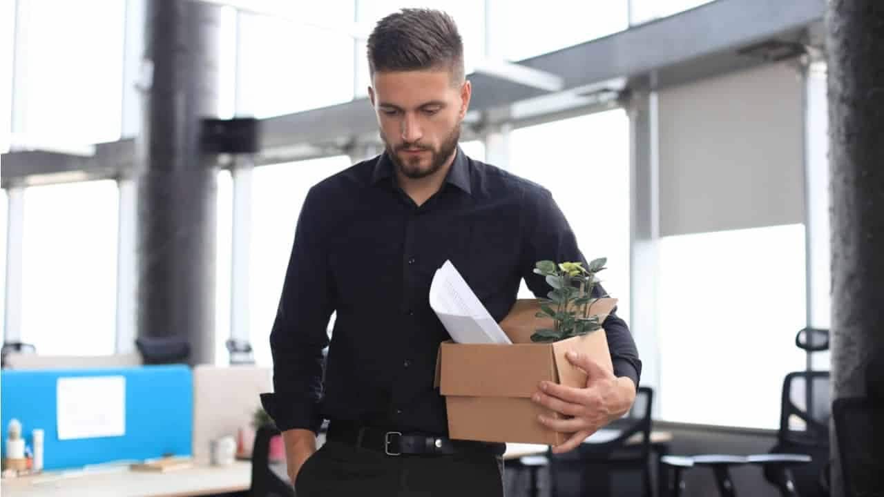 Um homem segurando uma caixa com itens de escritório