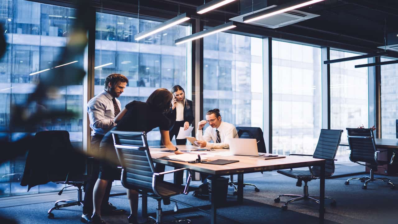 pessoas sentadas ao redor de uma mesa em um escritório