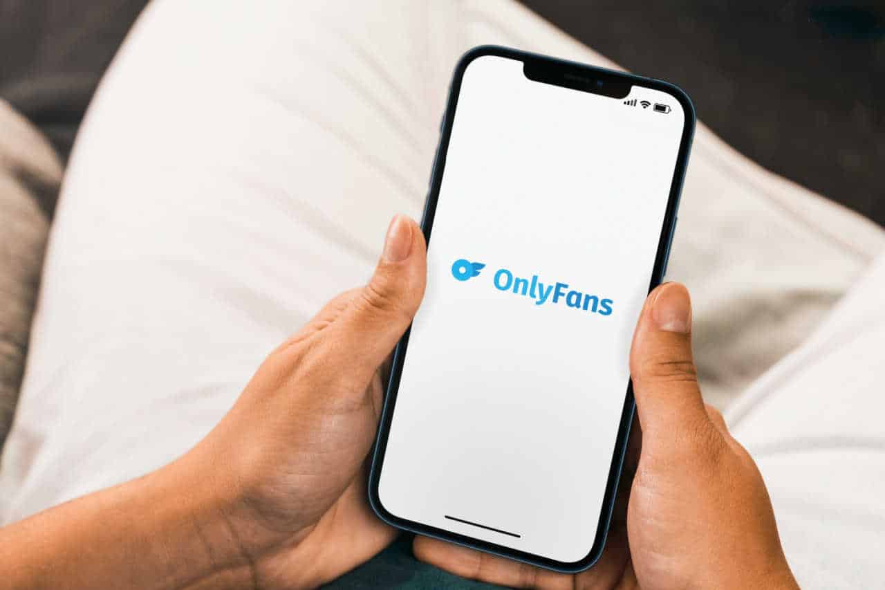 Mão segurando celular com aplicativo OnlyFans
