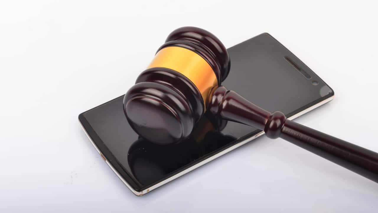 Martelo de juiz sobre um celular desligado