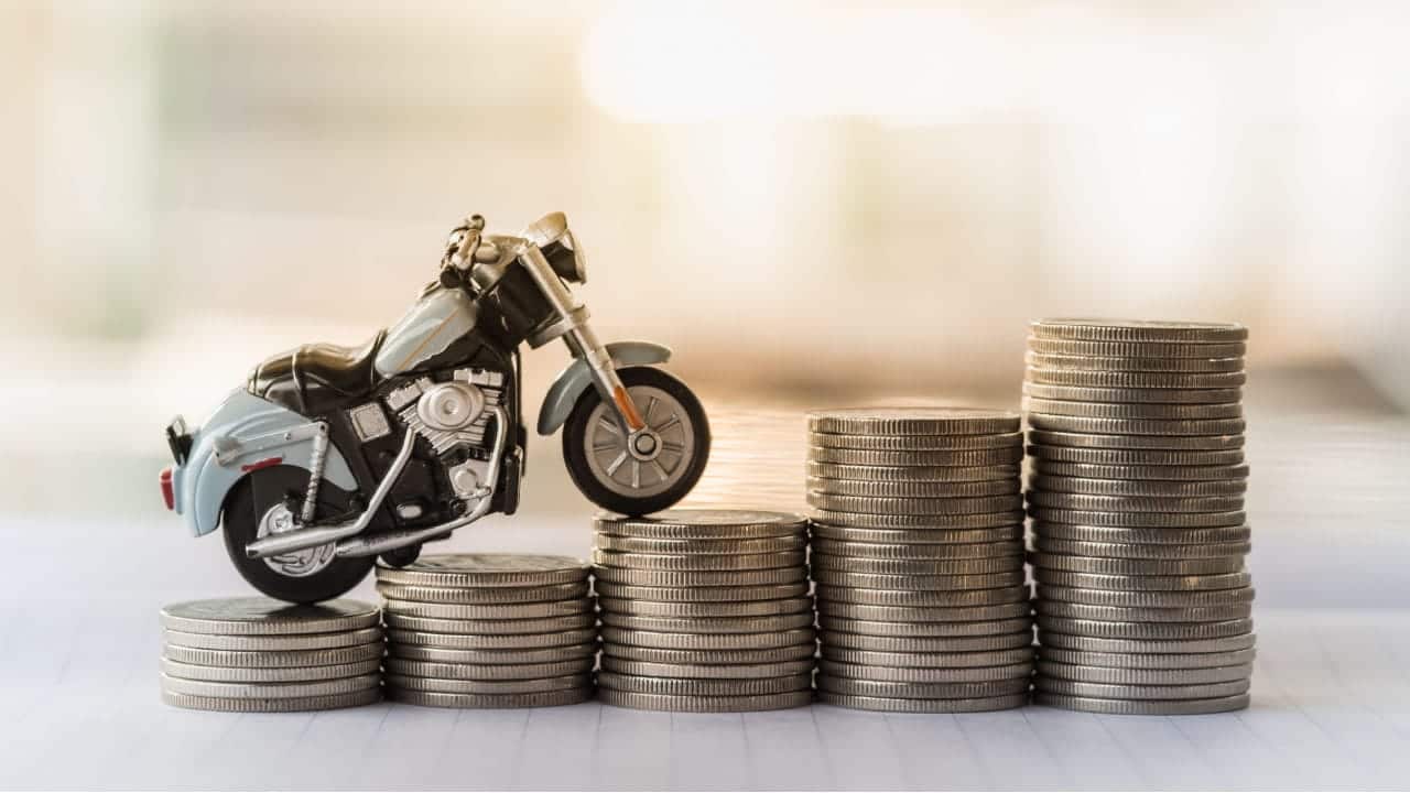 Miniatura de uma moto sobre pilhas de moedas organizadas em ordem crescente de tamanho