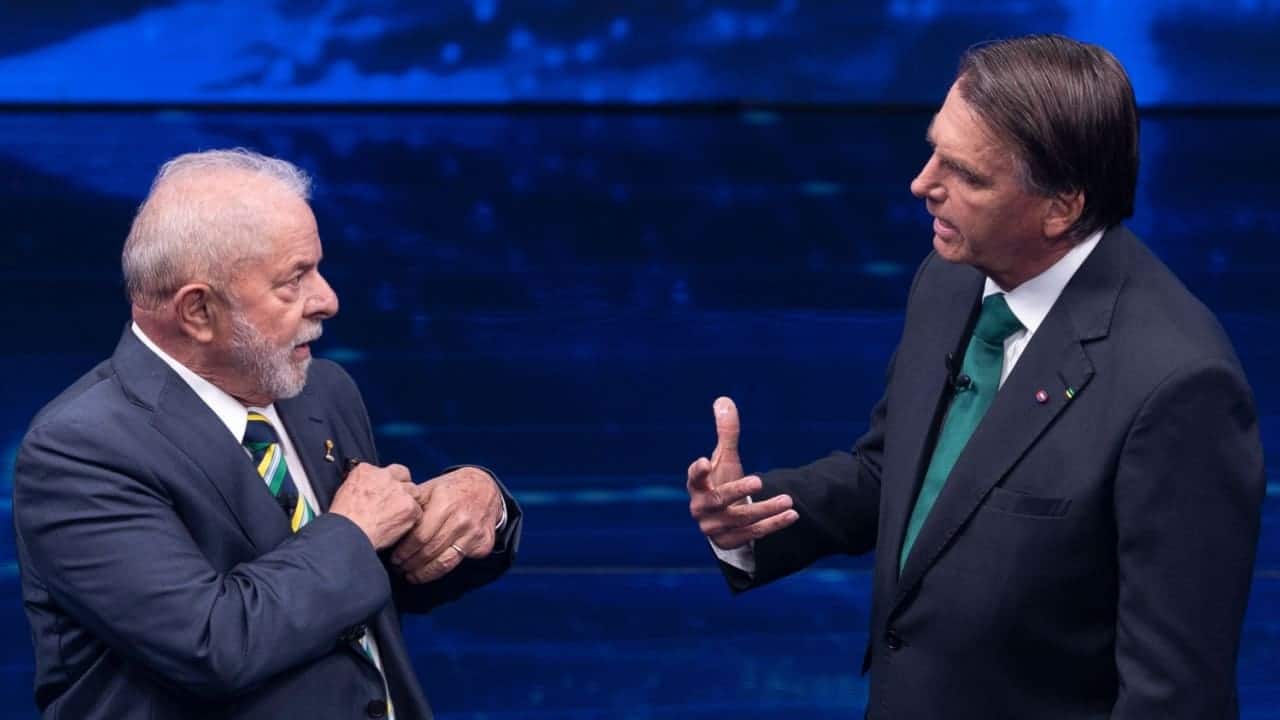 Lula e Bolsonaro gesticulando frente a frente durante debate presidencial
