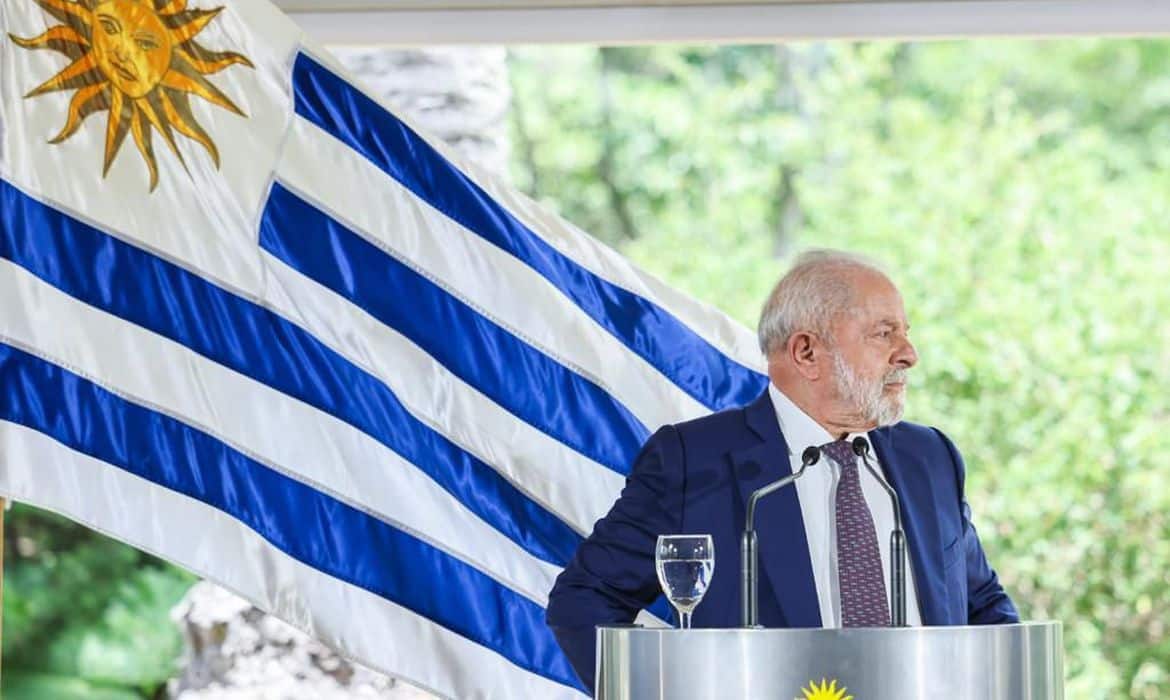 Lula em um púlpito com a bandeira do Uruguai atrás