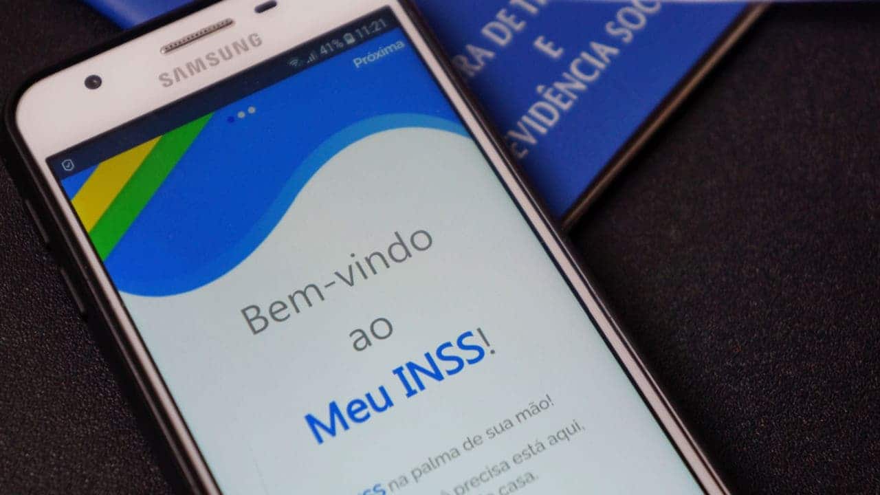 Apoiado em uma carteira de trabalho, celular exibe a tela inicial do aplicativo Meu INSS