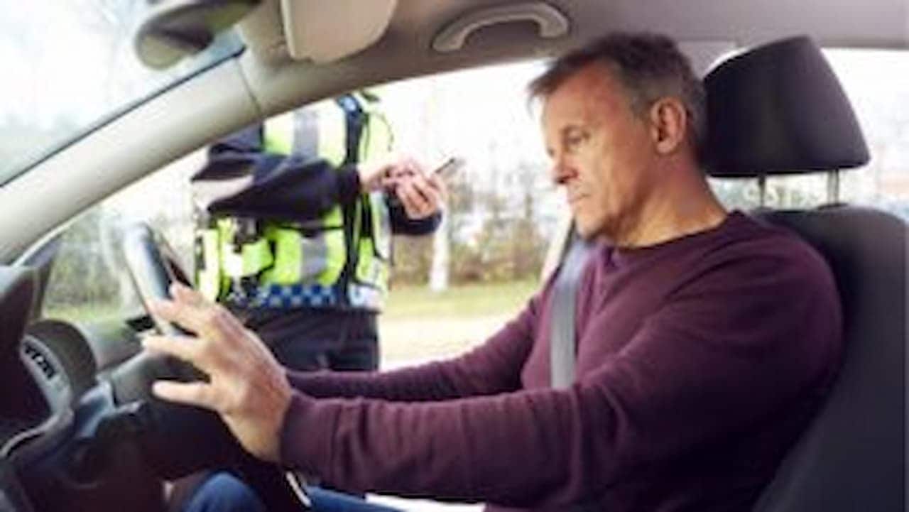 Homem sendo multado no carro por agente de trânsito