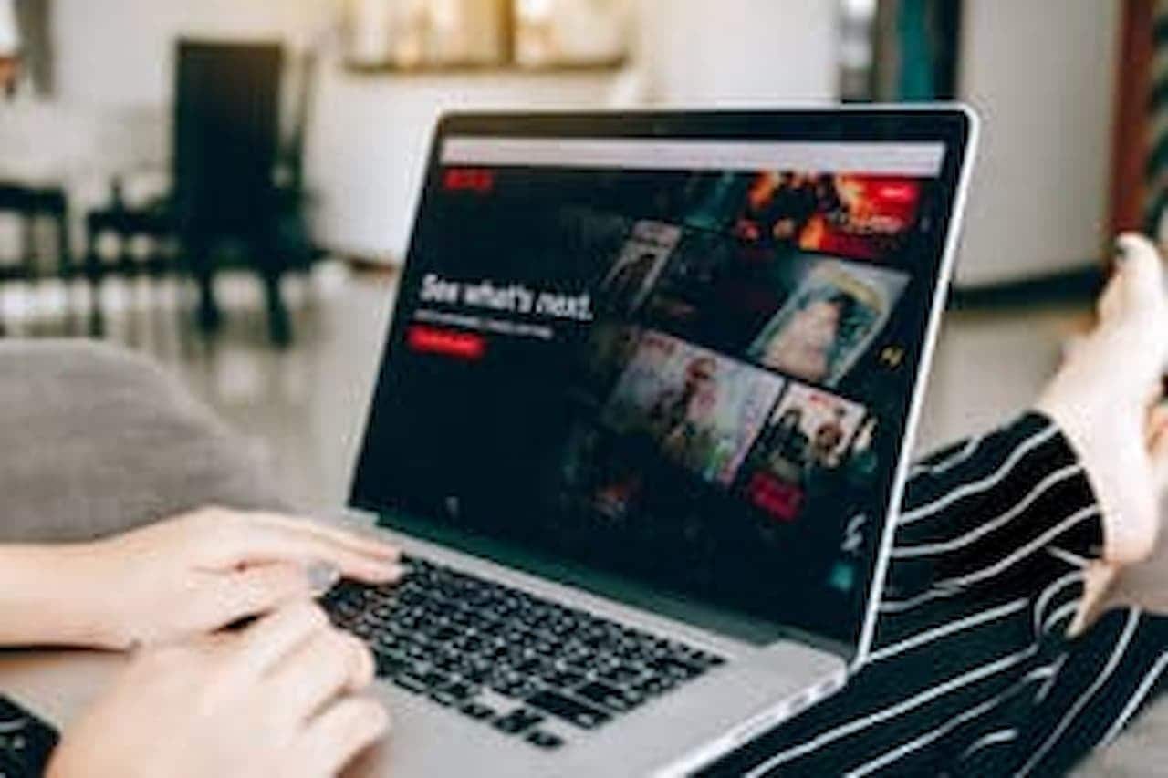 Notebook apoiado no colo de pessoa, com Netflix aberta