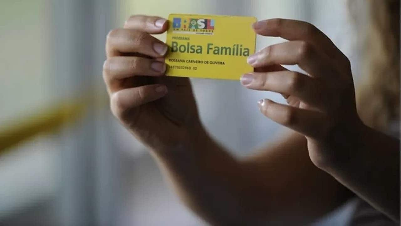 Mãos segurando cartão do Bolsa Família