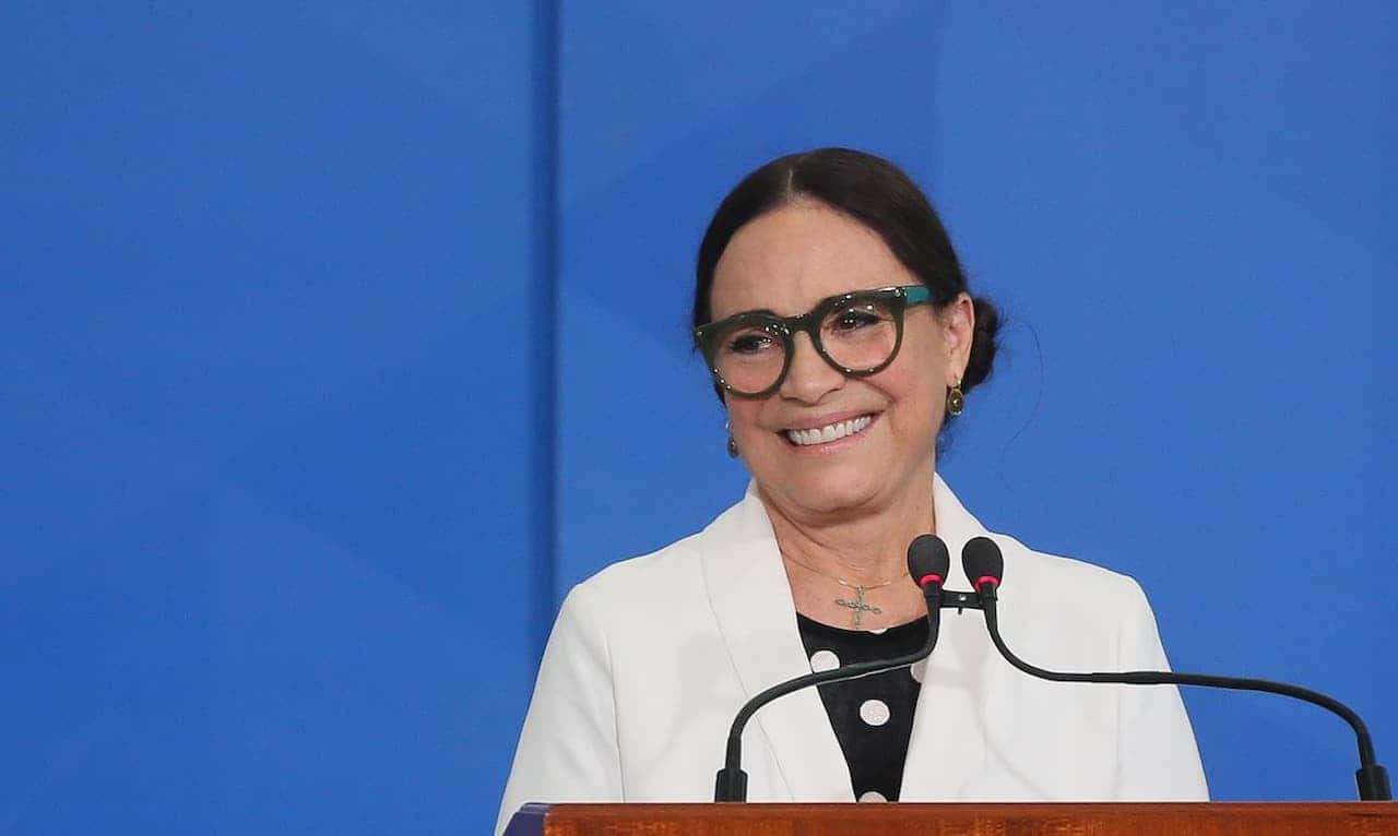imagem de Regina Duartem sorrindo em palanque de discurso