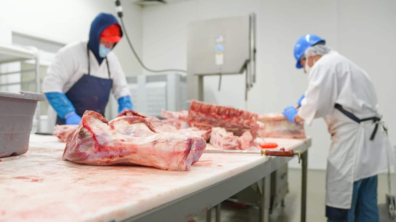 açougueiros cortam carne em uma mesa