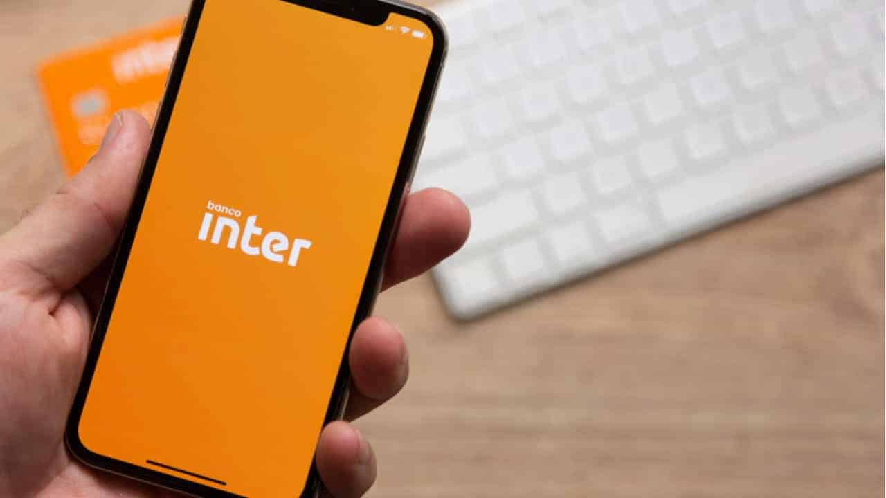 Pessoa segurando celular que exibe logo do banco Inter