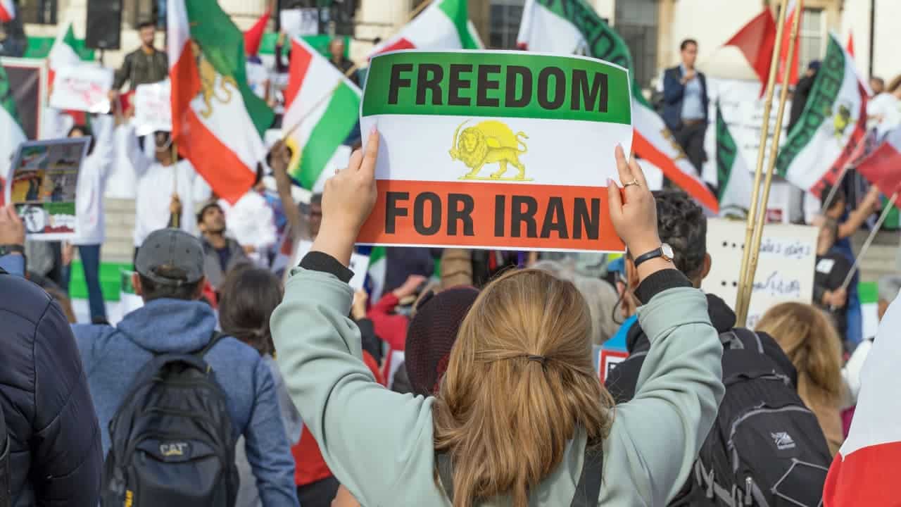 Protesto pela liberdade no regime do Irã, em Trafalgar Square, Londres. Mulher segura placa com bandeira do Irã, escrito "Freedom for Iran".