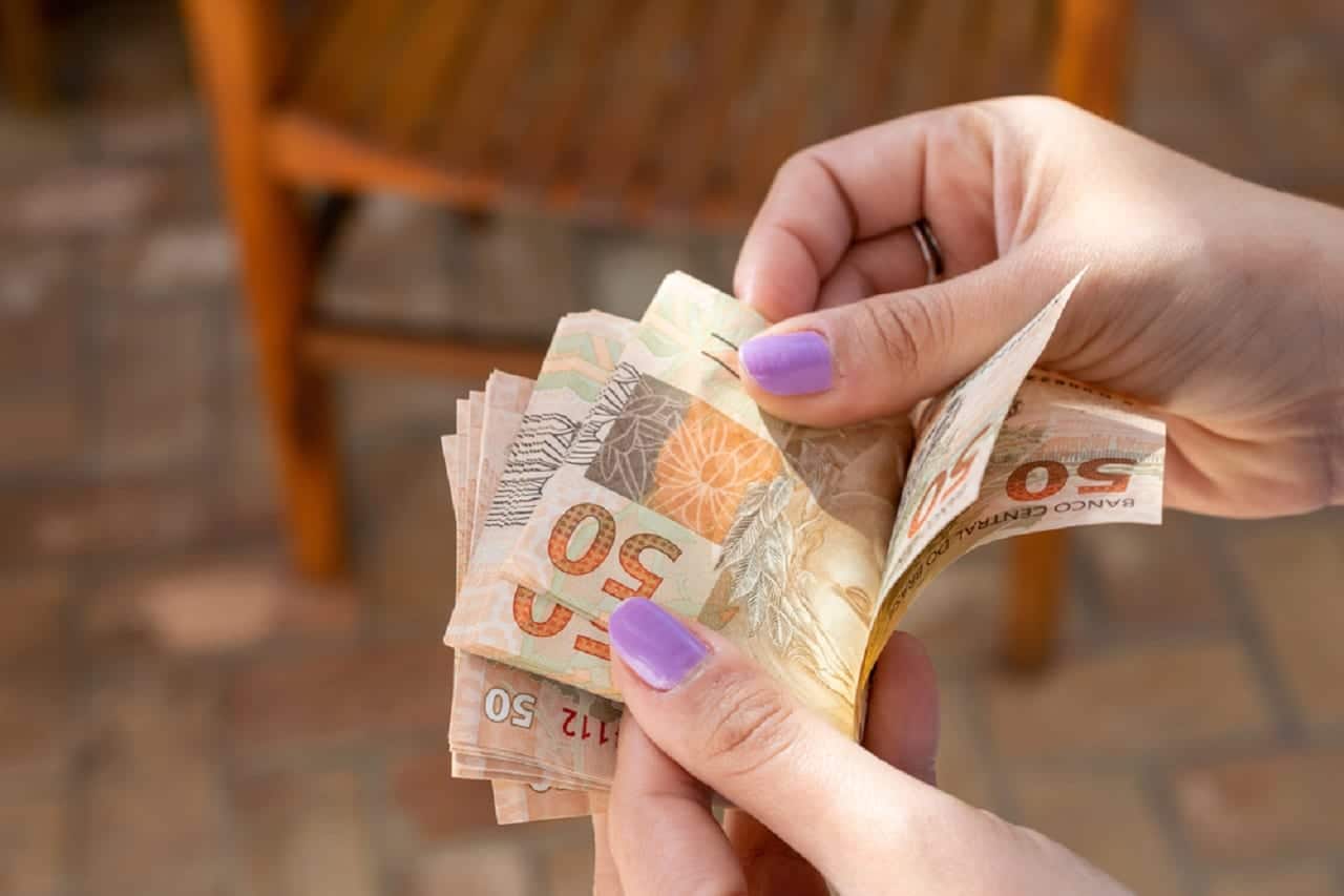 Imagem de uma pessoa contando notas de R$50.