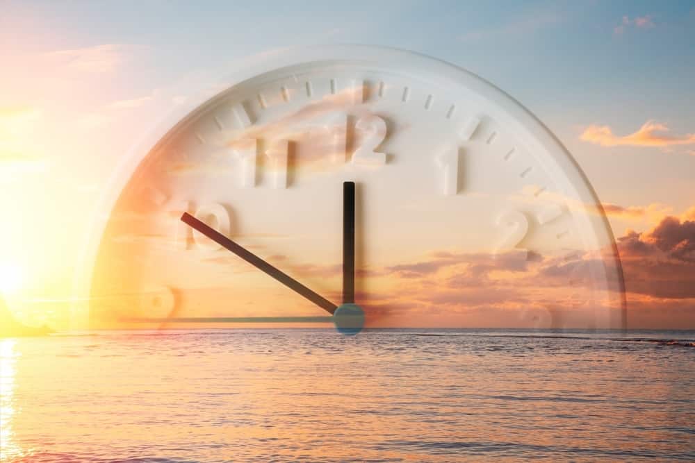 por do sol com um reológio para representar o horário de verão