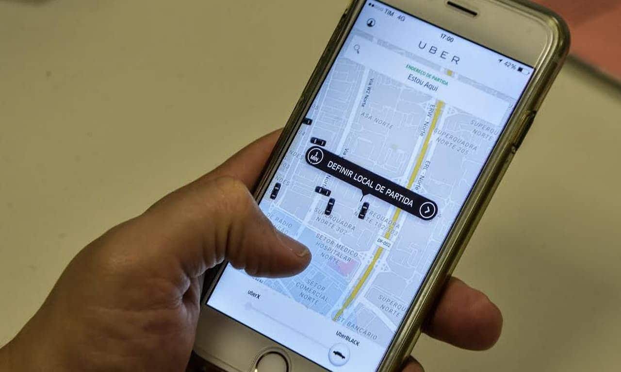 Mão segurando celular com aplicativo do Uber aberto