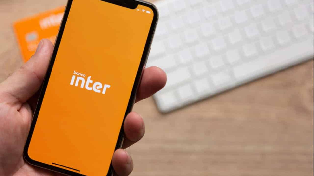 Pessoa segurando celular que exibe logo do banco Inter