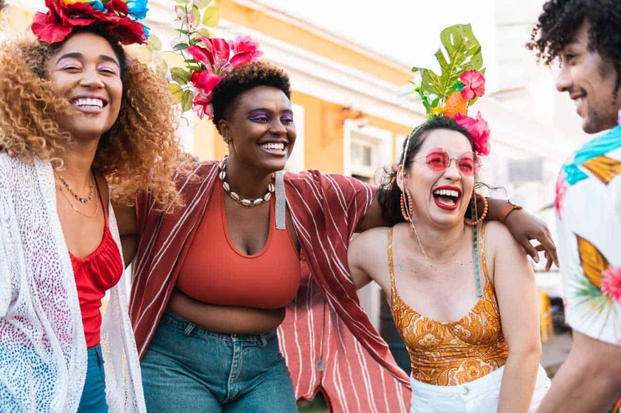 Quatro pessoas, sendo três mulheres e um homem, brincando carnaval de rua