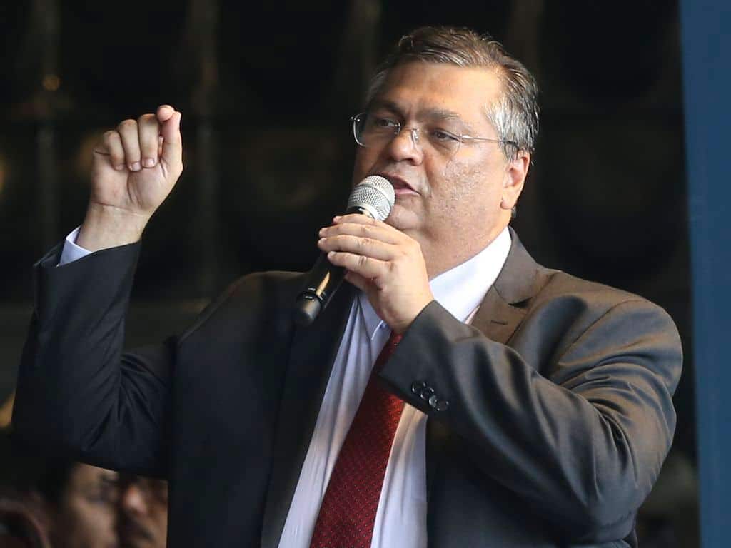Flávio Dino, Ministro da Justiça, discursando de terno e gravata. stf