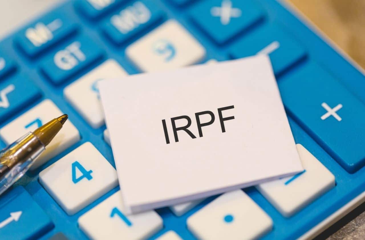 Folha branca escrito a sigla "IRPF" em cima de uma calculadora