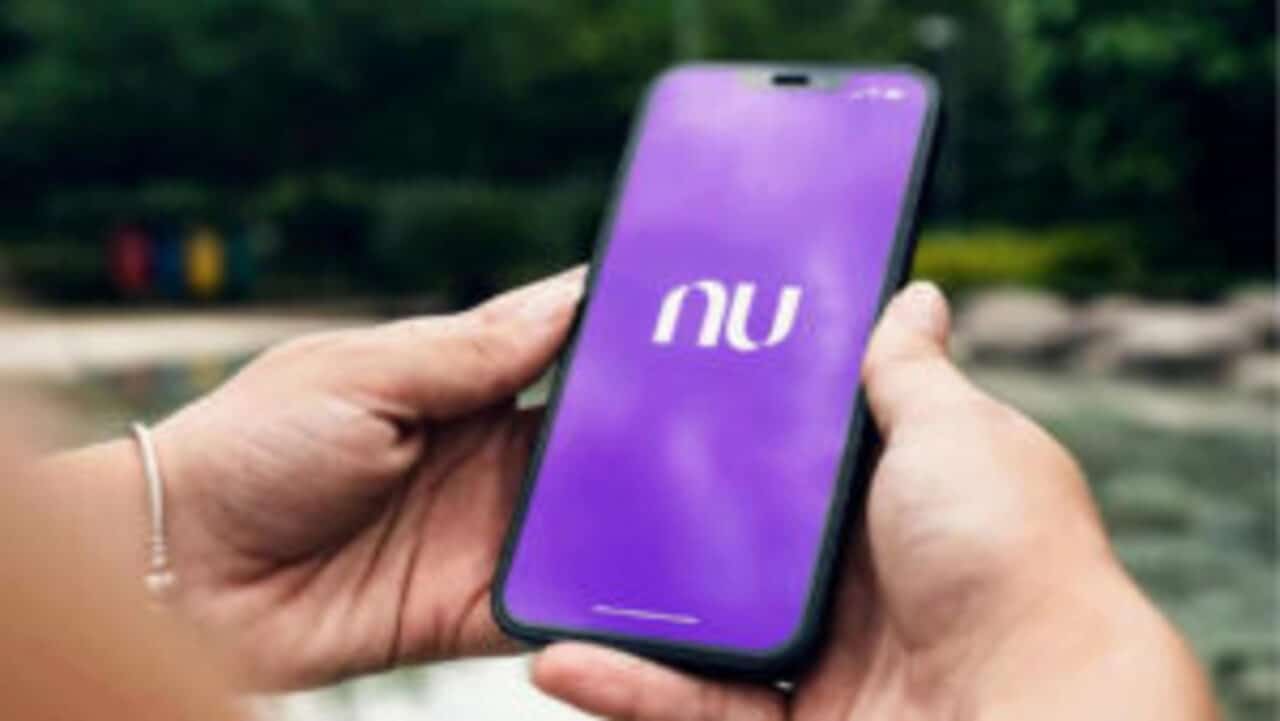 Mãos de uma pessoa segurando celular que mostra logo do Nubank