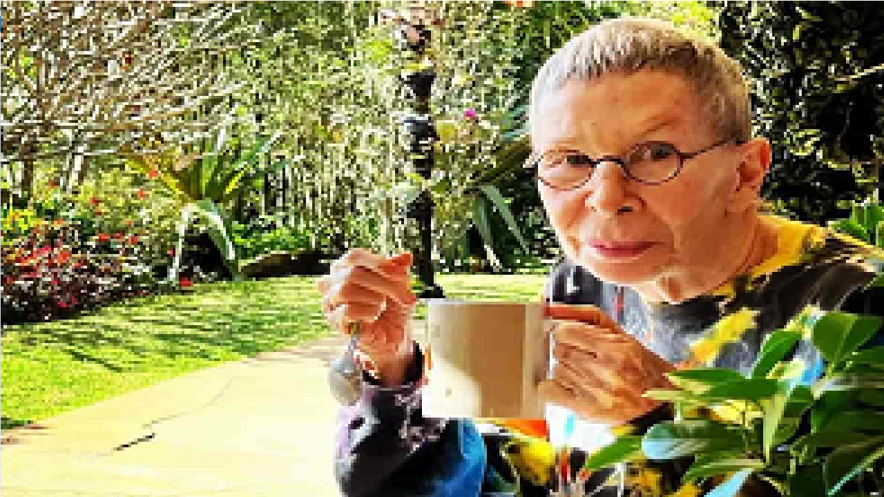 Imagem da cantora Rita Lee segurando uma caneca em um jardim