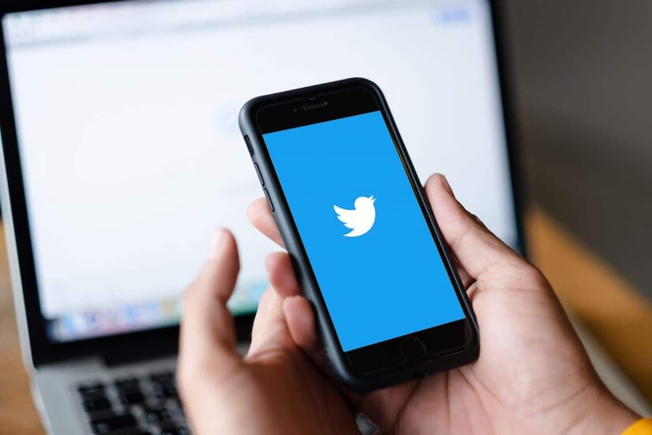 Mãos segurando smartphone com Twitter aberto